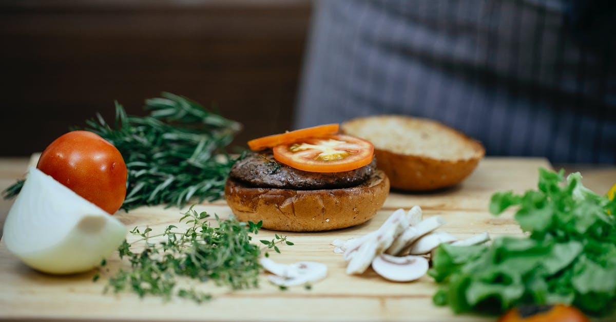Mushroom replacement in Beef Wellington - Crop cook at table with tomato on bun Mushroom replacement in Beef Wellington - Crop cook at table with tomato on bun