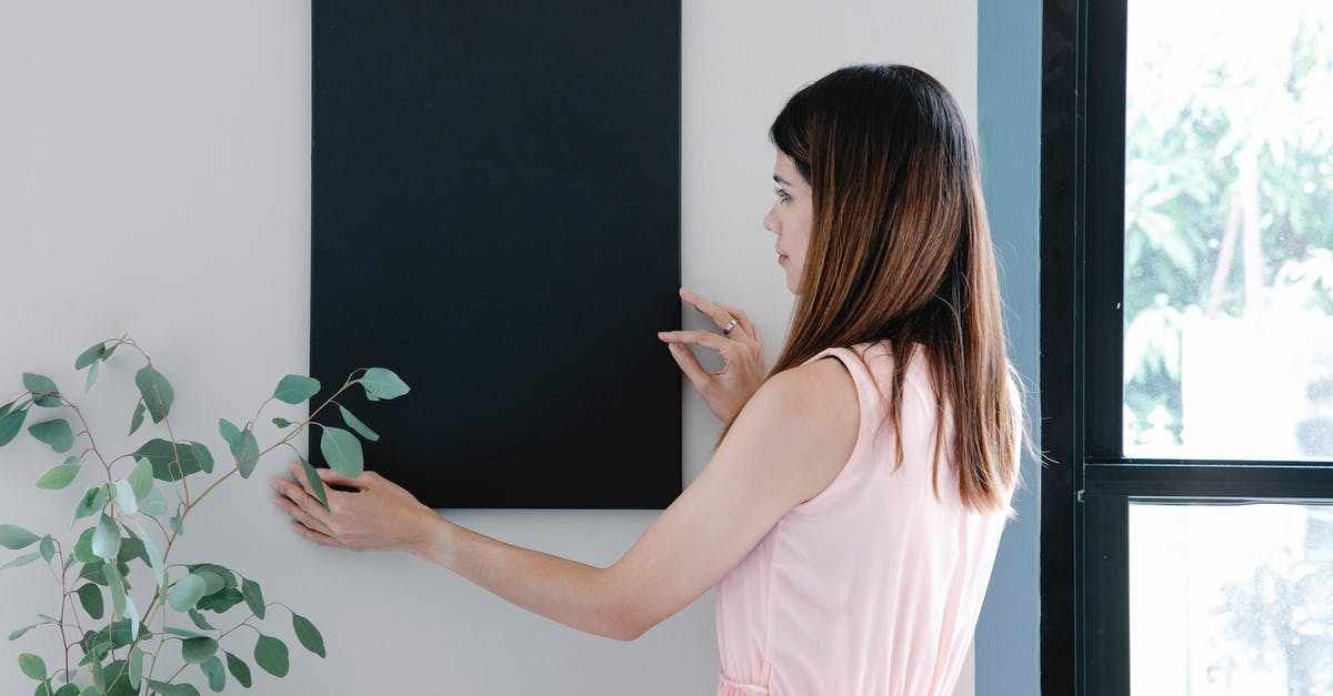 My hotpot has a stand attached to it - Back view of young female with long hair attaching empty rectangular frame on wall My hotpot has a stand attached to it - Back view of young female with long hair attaching empty rectangular frame on wall