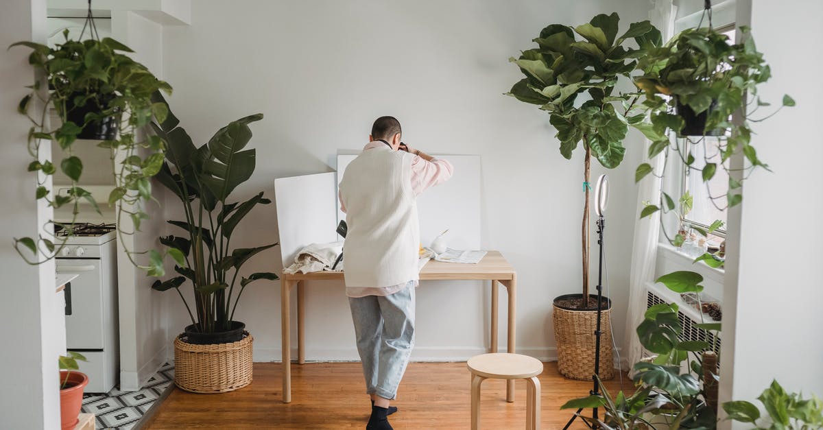 Mystery kitchen device with three finger loops, one attached to a sliding rod that passes through a ring - Back view of anonymous person taking photo on camera while standing on floor against desk in house with assorted plants Mystery kitchen device with three finger loops, one attached to a sliding rod that passes through a ring - Back view of anonymous person taking photo on camera while standing on floor against desk in house with assorted plants