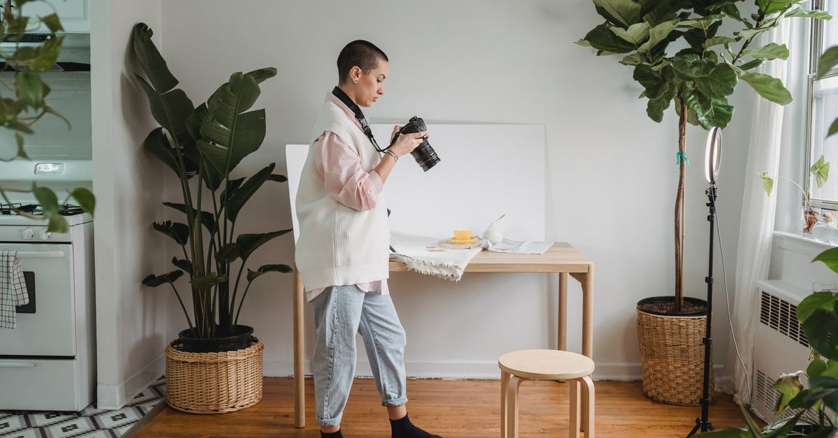 Mystery kitchen device with three finger loops, one attached to a sliding rod that passes through a ring - Side view of young woman watching digital photo camera on floor between potted plants in light house Mystery kitchen device with three finger loops, one attached to a sliding rod that passes through a ring - Side view of young woman watching digital photo camera on floor between potted plants in light house