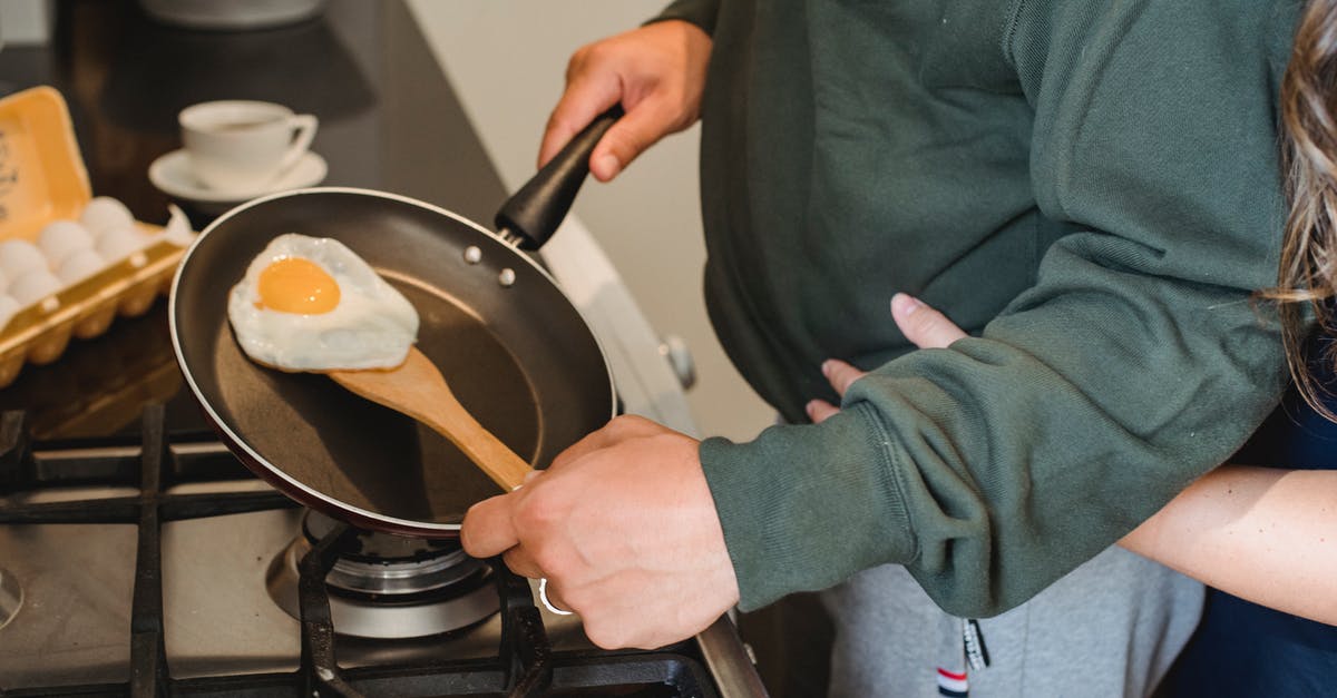 Need a gas cooker but have no gas supply - Crop anonymous female embarrassing man in casual clothes standing near gas stove with pan in hand and cooking fried egg for diner in kitchen at home Need a gas cooker but have no gas supply - Crop anonymous female embarrassing man in casual clothes standing near gas stove with pan in hand and cooking fried egg for diner in kitchen at home