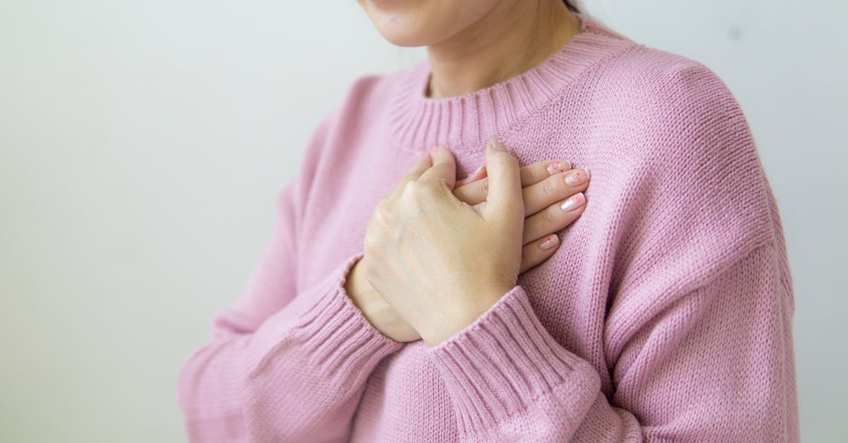New Red Potatoes have pink streaks inside - Content anonymous female wearing warm pink sweater standing on white background with crossed hands on chest in daylight in room