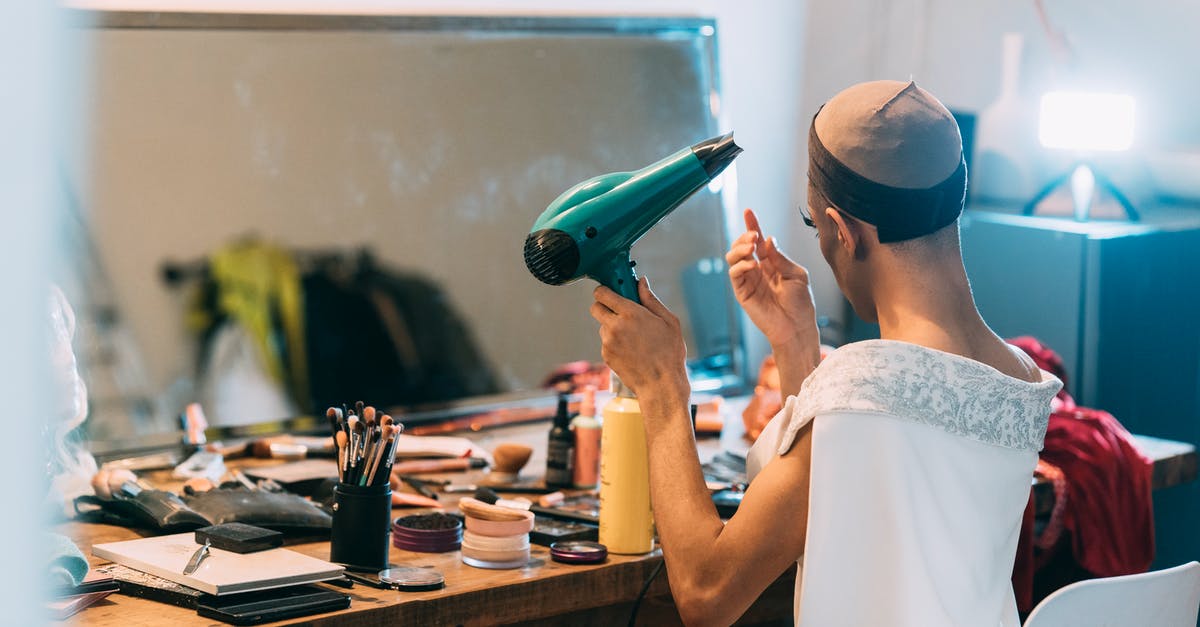 Non-dairy creamer, dry - Unrecognizable ethnic man drying hair in front of mirror Non-dairy creamer, dry - Unrecognizable ethnic man drying hair in front of mirror