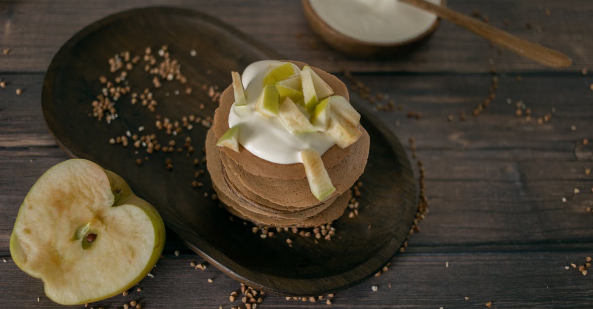 Oatmeal used in apple crisp topping - From above of tasty homemade pancakes made of buckwheat topped with sour cream and apples served on wooden table in kitchen