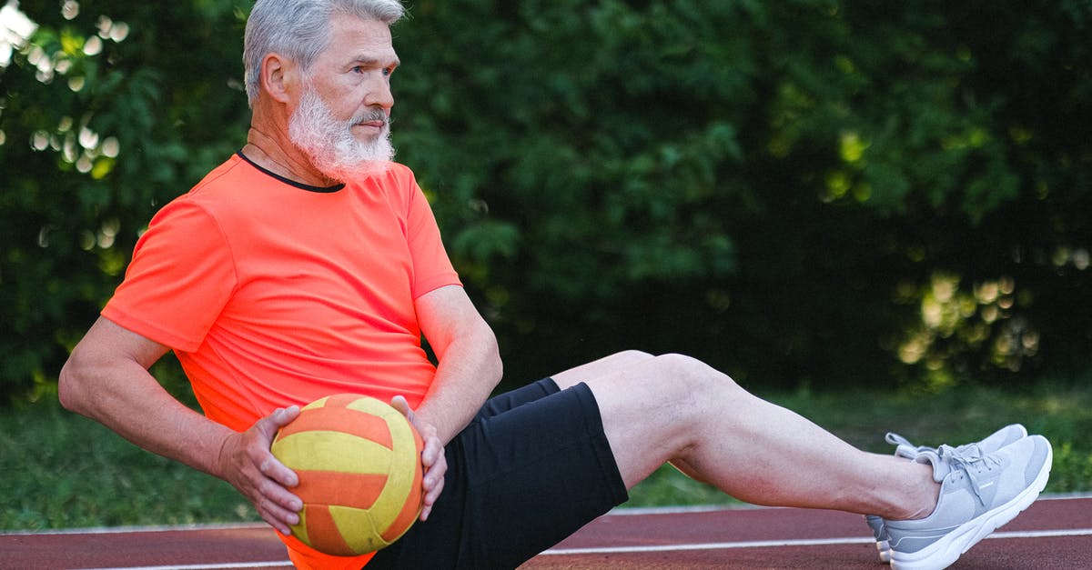 Old bread becomes sticky - Side view of active senior man with bread in sportswear doing fitness exercise with ball in daytime Old bread becomes sticky - Side view of active senior man with bread in sportswear doing fitness exercise with ball in daytime