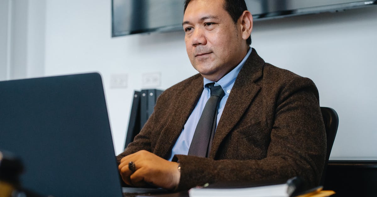 Online freely available cookbooks - Focused ethnic businessman using netbook while working in office Online freely available cookbooks - Focused ethnic businessman using netbook while working in office