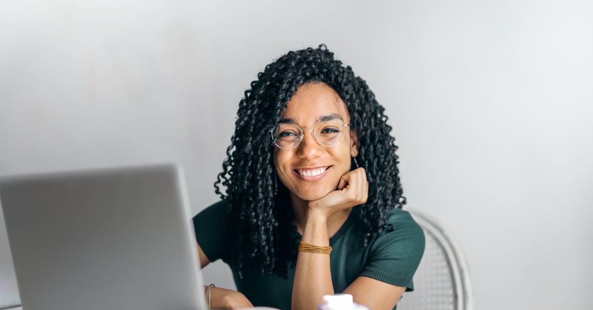 Online freely available cookbooks - Happy ethnic woman sitting at table with laptop Online freely available cookbooks - Happy ethnic woman sitting at table with laptop