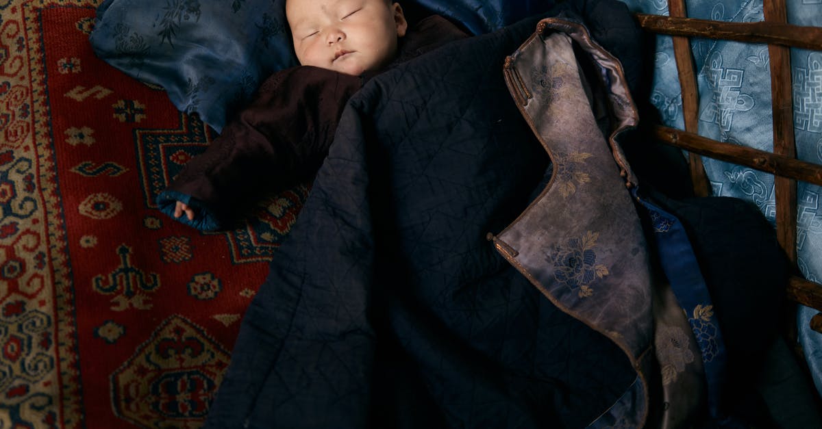 Oops left baby back ribs on warm instead of low for 7 hrs [duplicate] - From above of full length sleeping Asian infant in warm clothes lying on carpet under adult man jacket with floral backing