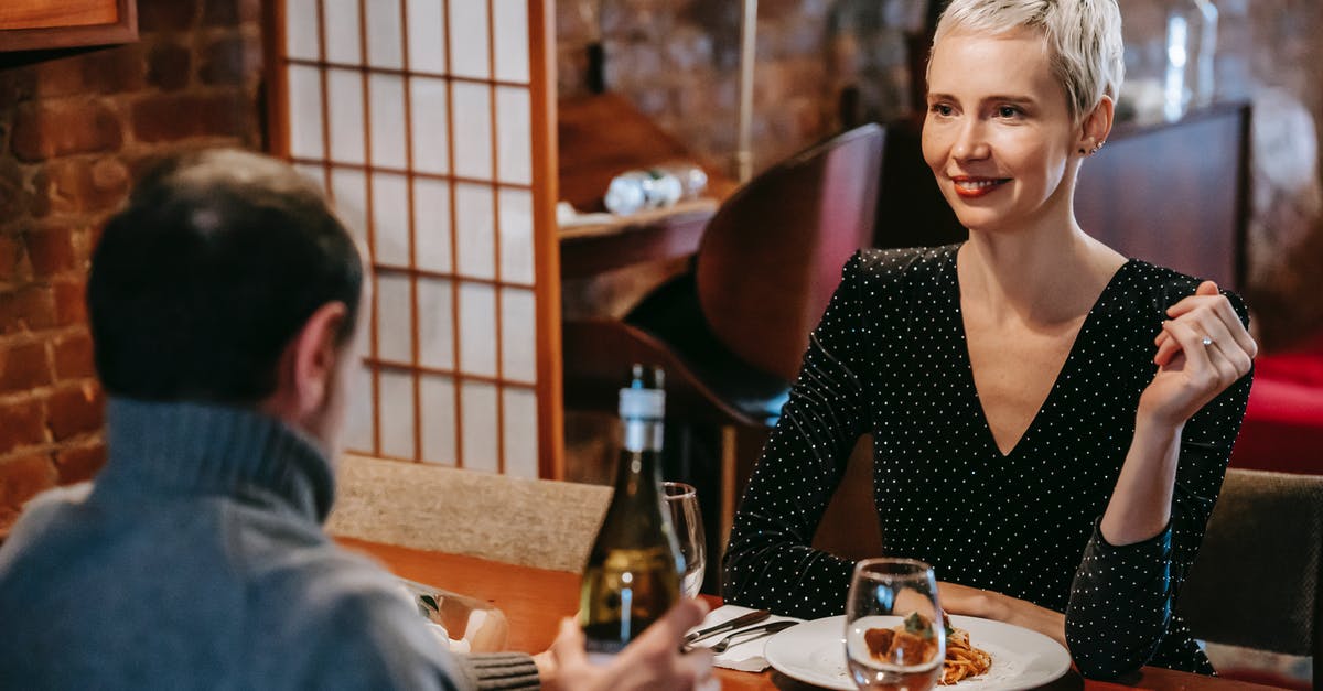 Opening wine bottle with rounded top using a waiter's friend - Couple having dinner with pasta and wine in room Opening wine bottle with rounded top using a waiter's friend - Couple having dinner with pasta and wine in room