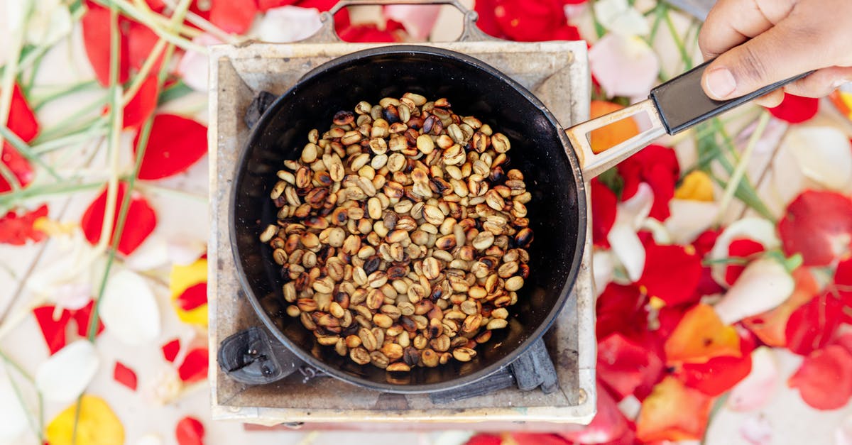 Options for non-stick frying pans - not using teflon - Top view of crop unrecognizable cook frying halved brown and golden crunchy peanuts on old portable gas stove while holding handle of frying pan above colorful oilcloth on table Options for non-stick frying pans - not using teflon - Top view of crop unrecognizable cook frying halved brown and golden crunchy peanuts on old portable gas stove while holding handle of frying pan above colorful oilcloth on table