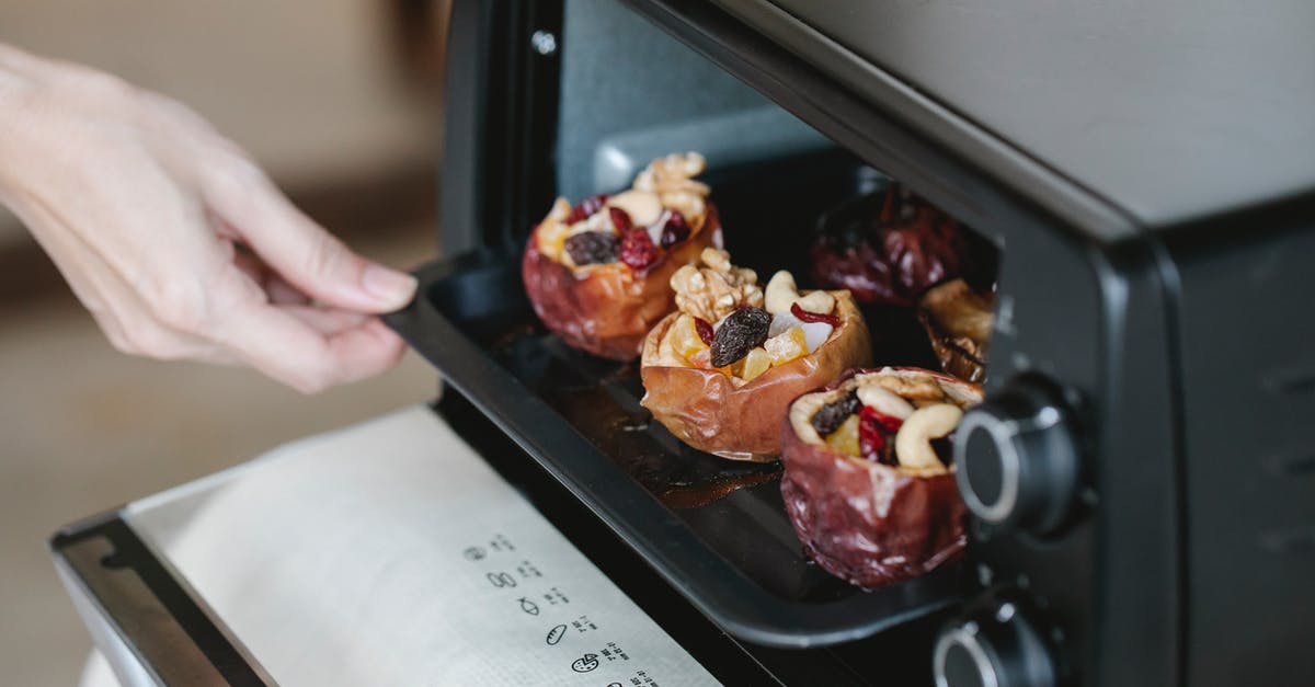 Oven baked cod fillets get soaked in their own liquid - Faceless cook getting out baking tray with delicious filled baked apples of electric oven at home Oven baked cod fillets get soaked in their own liquid - Faceless cook getting out baking tray with delicious filled baked apples of electric oven at home