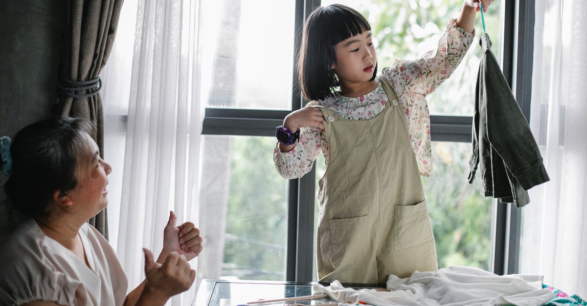 oven cleaning help and tips - Happy Asian woman showing like gesture while granddaughter organizing clothes on hanger at home oven cleaning help and tips - Happy Asian woman showing like gesture while granddaughter organizing clothes on hanger at home