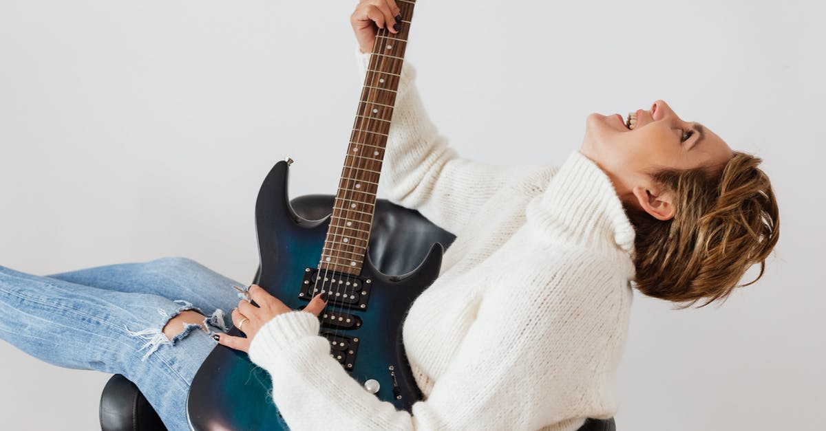 Oven does not have a temperature notification sound - Side view of cheerful short haired female in casual clothes laughing while playing electric guitar in comfortable armchair against white background Oven does not have a temperature notification sound - Side view of cheerful short haired female in casual clothes laughing while playing electric guitar in comfortable armchair against white background