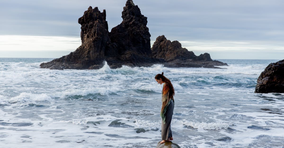 Over watered single layer - Side view of lonely sad female standing on stone in front of storming ocean Over watered single layer - Side view of lonely sad female standing on stone in front of storming ocean