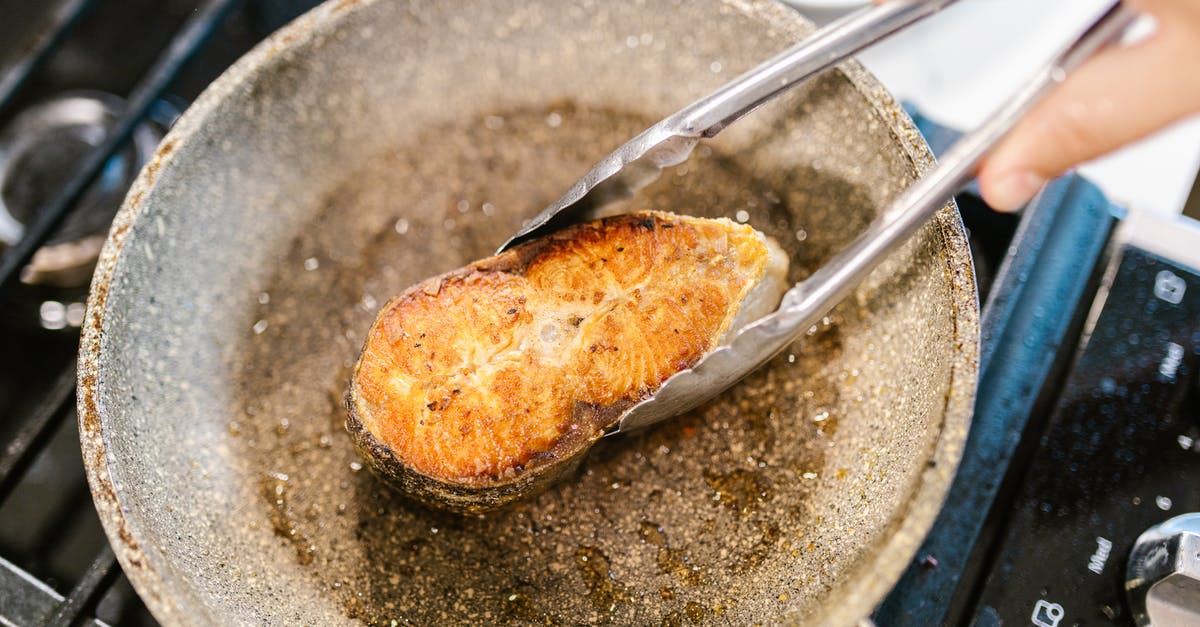 Pan-frying fish filets with skin on - Holding Fish Meat on Pan with Pincers Pan-frying fish filets with skin on - Holding Fish Meat on Pan with Pincers