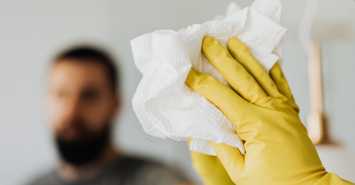 Paper towel gets completely dark after I wipe my Dutch oven [duplicate] - Unrecognizable bearded male wearing yellow latex gloves wiping mirror with napkin in bathroom at home