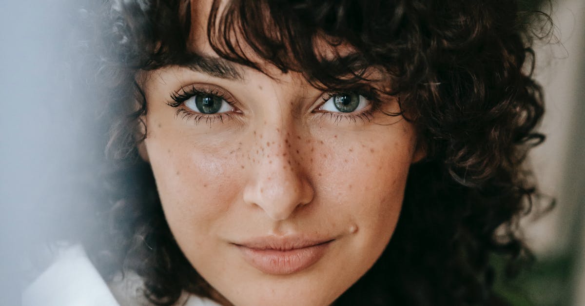 Parsley: flat-leaf or curly? - Headshot of attractive female with dark curly hair looking at camera against green leaves on blurred background in light room Parsley: flat-leaf or curly? - Headshot of attractive female with dark curly hair looking at camera against green leaves on blurred background in light room