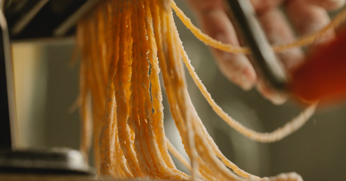 Pasta edges break when being rolled in pasta machine - Crop cook using pasta machine while preparing spaghetti Pasta edges break when being rolled in pasta machine - Crop cook using pasta machine while preparing spaghetti
