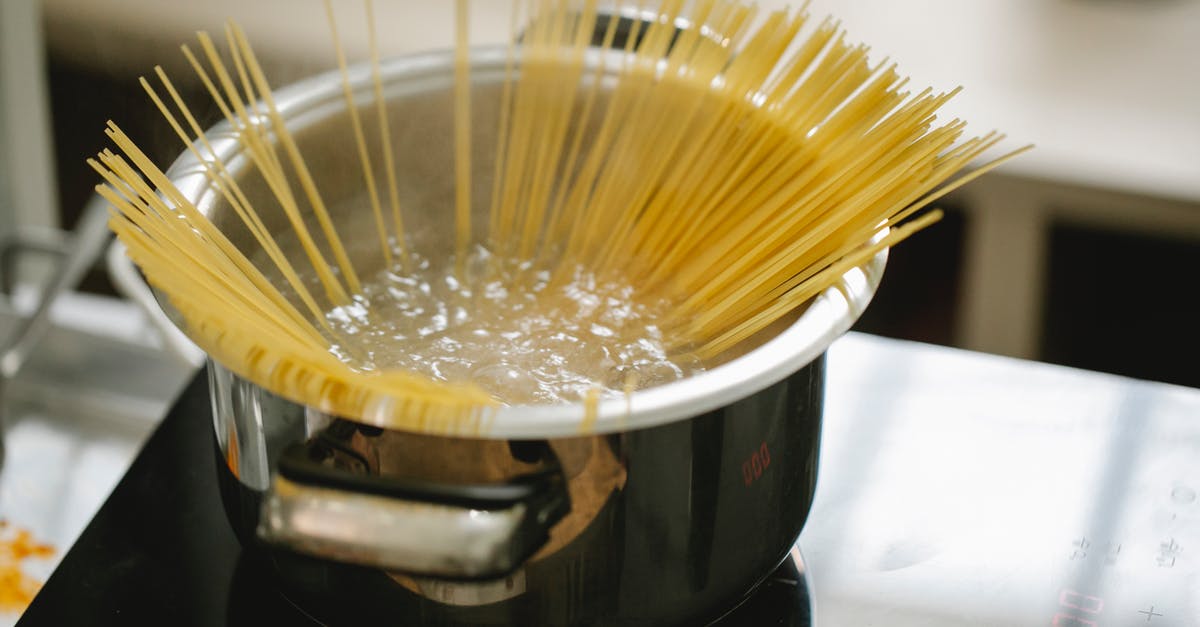 Pasta: is simmering equivalent to roiling boil? - Raw spaghetti cooked in boiling water in saucepan placed on stove in light kitchen Pasta: is simmering equivalent to roiling boil? - Raw spaghetti cooked in boiling water in saucepan placed on stove in light kitchen