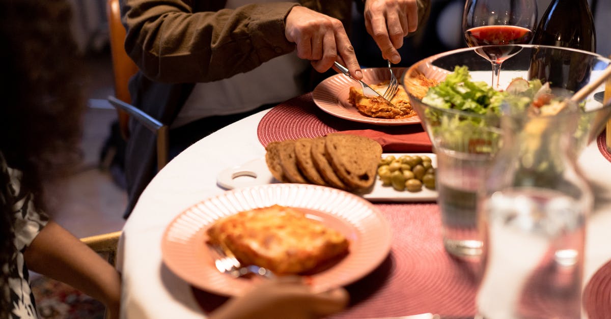 Pasticcio vs Lasagna - Person Cutting Lasagna with Knife During Dinner at Table 
