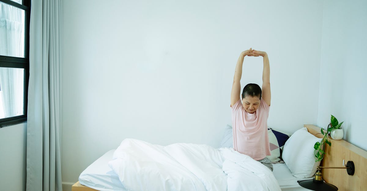 Pizza dough is too soft to stretch well - Ethnic female stretching body on bed in morning Pizza dough is too soft to stretch well - Ethnic female stretching body on bed in morning