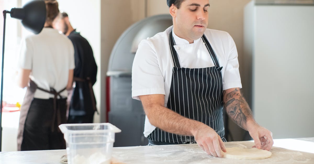 Pizza dough keeps breaking through plastic - Man in Striped Apron Making Dough Pizza dough keeps breaking through plastic - Man in Striped Apron Making Dough