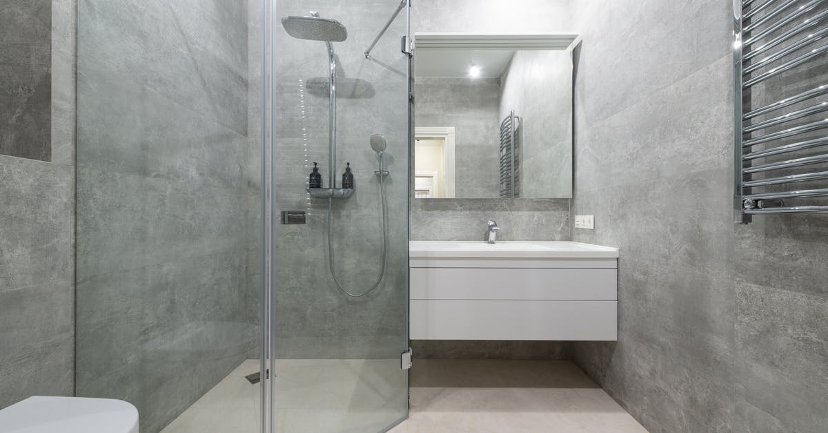 Placing a ceramic bowl over stainless steel saucepan - Modern shower room interior with glass walls against washstand Placing a ceramic bowl over stainless steel saucepan - Modern shower room interior with glass walls against washstand