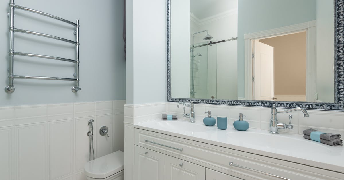 Placing a ceramic bowl over stainless steel saucepan - Contemporary bathroom with toilet bowl and cabinet with towels against washstands under mirror in hotel Placing a ceramic bowl over stainless steel saucepan - Contemporary bathroom with toilet bowl and cabinet with towels against washstands under mirror in hotel
