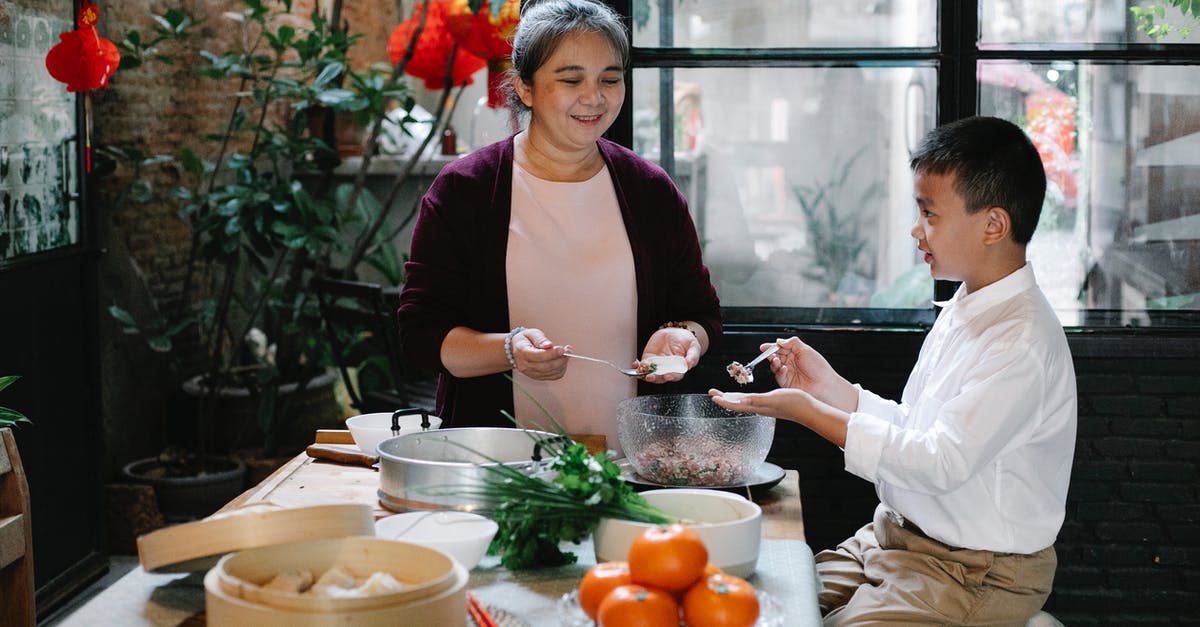 Please help identifying this herb - Side view of positive Asian preteen boy sitting at table in kitchen and helping smiling mature grandmother to prepare traditional Chinese dumplings for dinner Please help identifying this herb - Side view of positive Asian preteen boy sitting at table in kitchen and helping smiling mature grandmother to prepare traditional Chinese dumplings for dinner