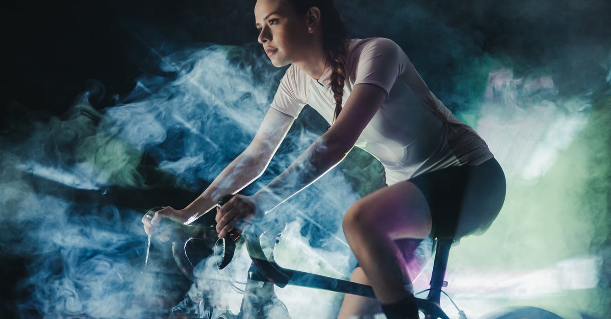 Polymer fume fever probably detected - Young female athlete in active wear with concentrated gaze riding bicycle in shiny cloud while looking forward Polymer fume fever probably detected - Young female athlete in active wear with concentrated gaze riding bicycle in shiny cloud while looking forward