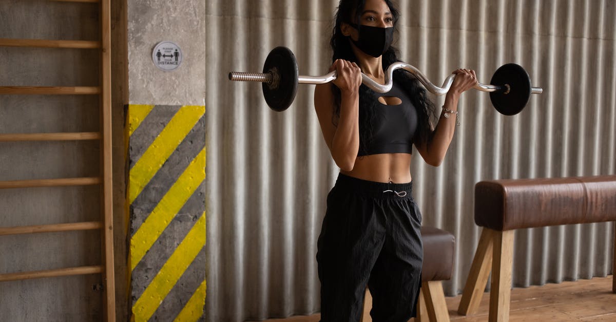 Pork belly strips and ribs - Black sportswoman in face mask exercising with barbell in gymnasium Pork belly strips and ribs - Black sportswoman in face mask exercising with barbell in gymnasium