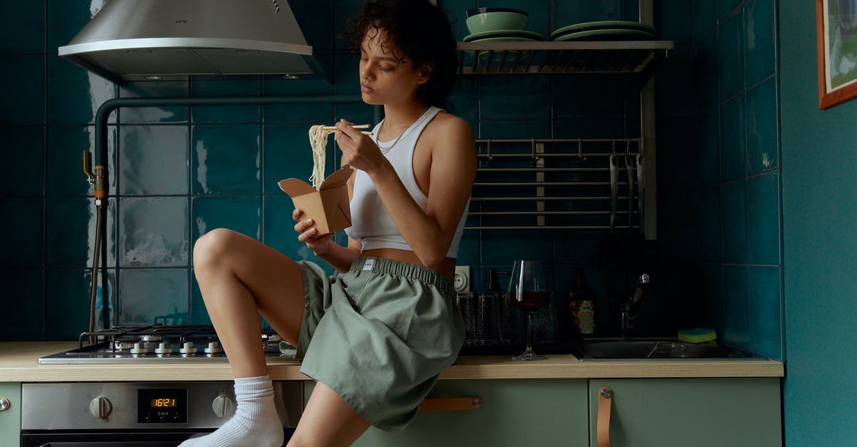 Pot stick to induction top not able to remove it plz advice - Young female in gray shorts and white top and socks eating noodles with sticks from carton box while sitting in kitchen in modern apartment Pot stick to induction top not able to remove it plz advice - Young female in gray shorts and white top and socks eating noodles with sticks from carton box while sitting in kitchen in modern apartment