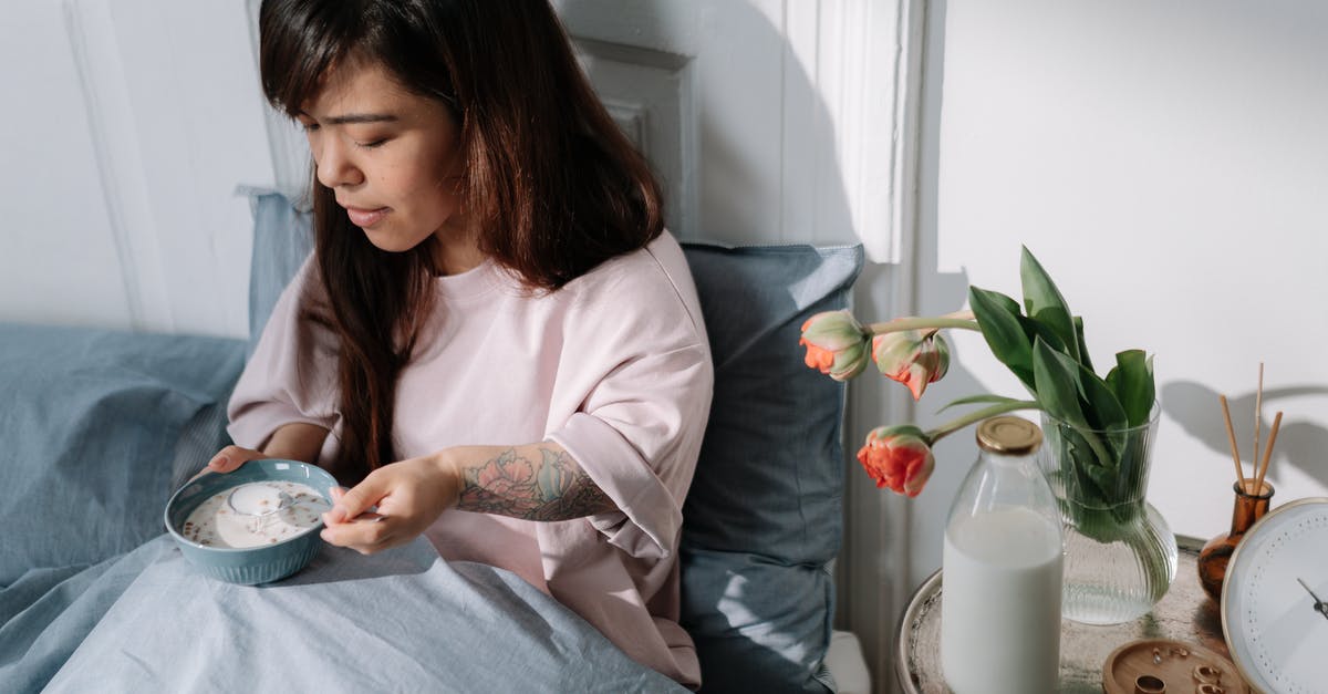 Premixed Bircher muesli (cereal) - soak overnight or ready-to-eat? - Woman eating cereal with milk sitting in a bed Premixed Bircher muesli (cereal) - soak overnight or ready-to-eat? - Woman eating cereal with milk sitting in a bed