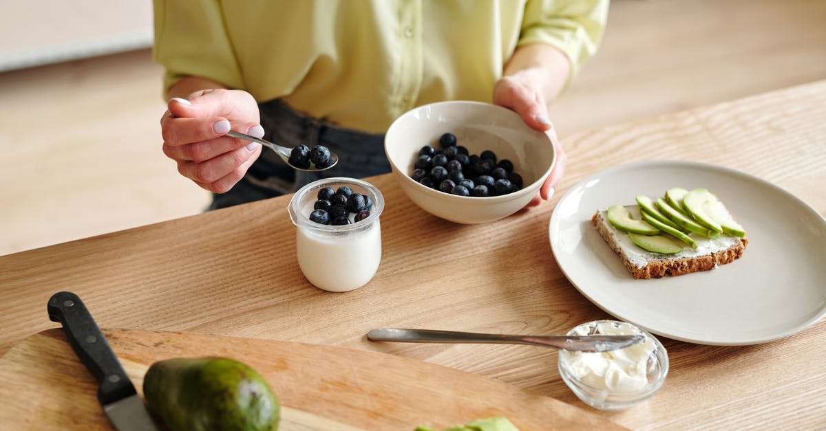 Premixed ingredients for yogurt - Person Putting Blueberries on Yogurt Premixed ingredients for yogurt - Person Putting Blueberries on Yogurt