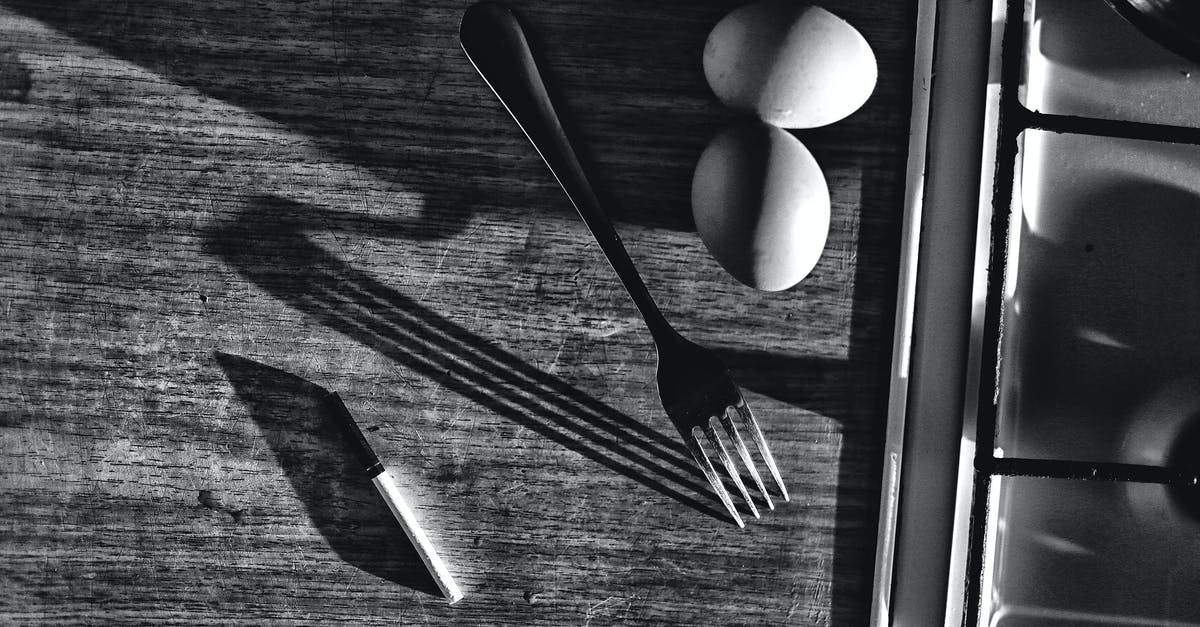Prevent scrambled eggs from sticking to stainless steel - Black and white top view of chicken eggs with fork and knife on table with shades against sink at home Prevent scrambled eggs from sticking to stainless steel - Black and white top view of chicken eggs with fork and knife on table with shades against sink at home