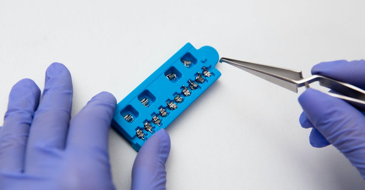 Prevent scrambled eggs from sticking to stainless steel - Hands of dentist in lilac latex medical gloves with dental tweezers and set of metal brace system Prevent scrambled eggs from sticking to stainless steel - Hands of dentist in lilac latex medical gloves with dental tweezers and set of metal brace system