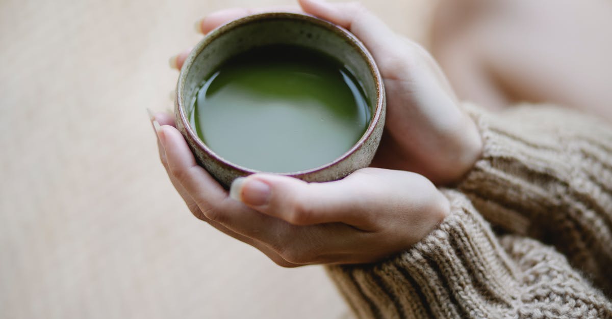 Preventing matcha deposits - High angle of crop anonymous female in knitwear with ceramic cup of hot matcha tea Preventing matcha deposits - High angle of crop anonymous female in knitwear with ceramic cup of hot matcha tea