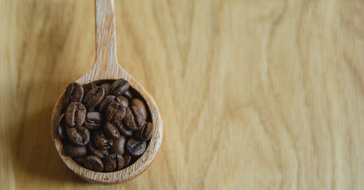 Principles of full flavour in dishes - Top view of wooden cup full of coffee beans located on wooden table Principles of full flavour in dishes - Top view of wooden cup full of coffee beans located on wooden table