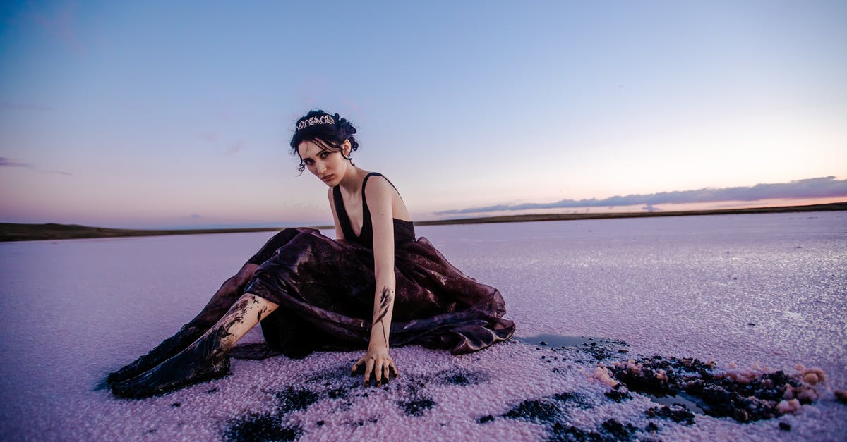 Problem Frozen flour - Full body of elegant female covered with black oil looking at camera while sitting on contaminated snowy terrain in nature Problem Frozen flour - Full body of elegant female covered with black oil looking at camera while sitting on contaminated snowy terrain in nature