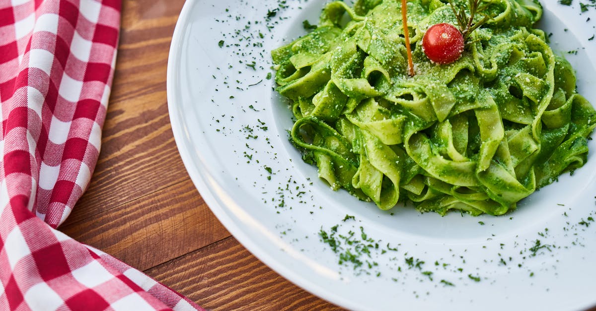 Processed cheese in pesto - Flat Pasta Noodle With Green Sauce Dish and Cherry Tomato on Top Processed cheese in pesto - Flat Pasta Noodle With Green Sauce Dish and Cherry Tomato on Top