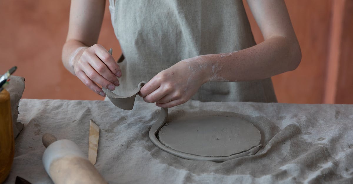 Pumpkin Roll Technique - Unrecognizable skilled female master in apron standing near table with rolling pin and working with clay while making crockery during work in pottery workshop with blurred background