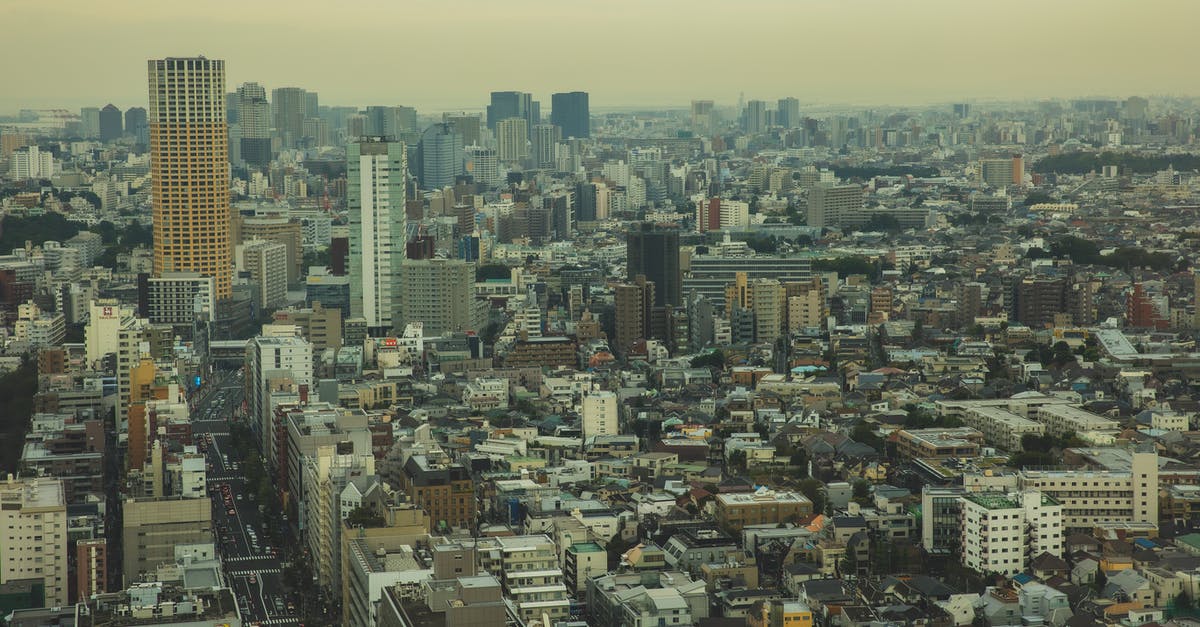 "tall can of evaporated milk", how big is it? - Drone view of tall dense contemporary houses of big city under smog and cloudy sky "tall can of evaporated milk", how big is it? - Drone view of tall dense contemporary houses of big city under smog and cloudy sky