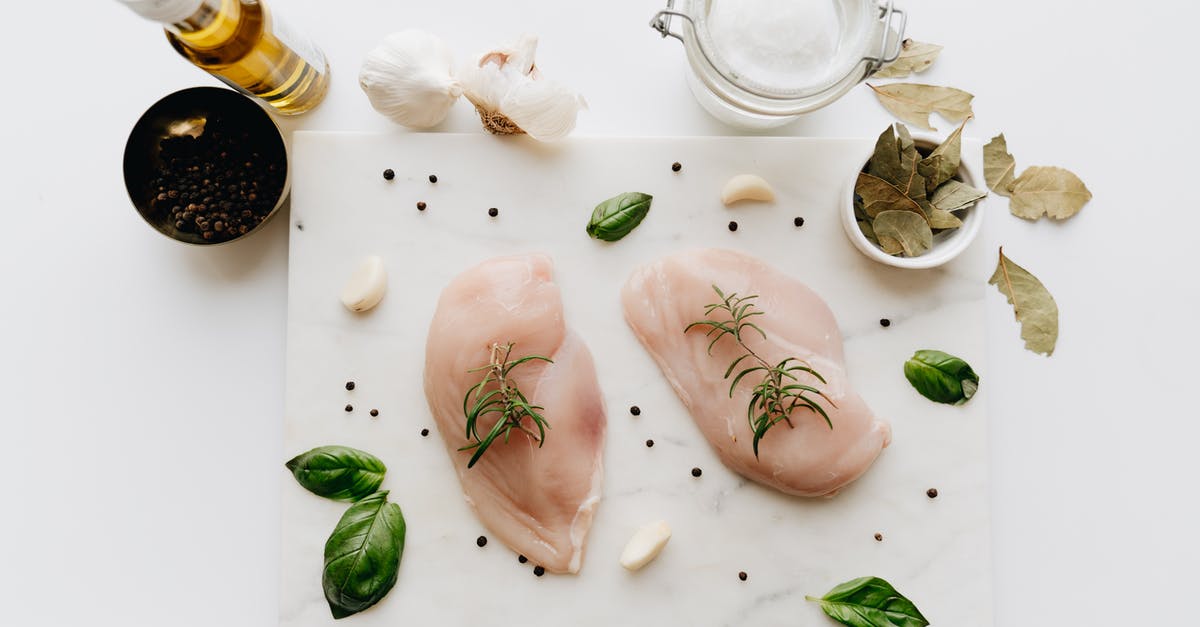 Raw garlic in Sunflower oil - Raw Chicken Breast with Rosemary on the Table Raw garlic in Sunflower oil - Raw Chicken Breast with Rosemary on the Table