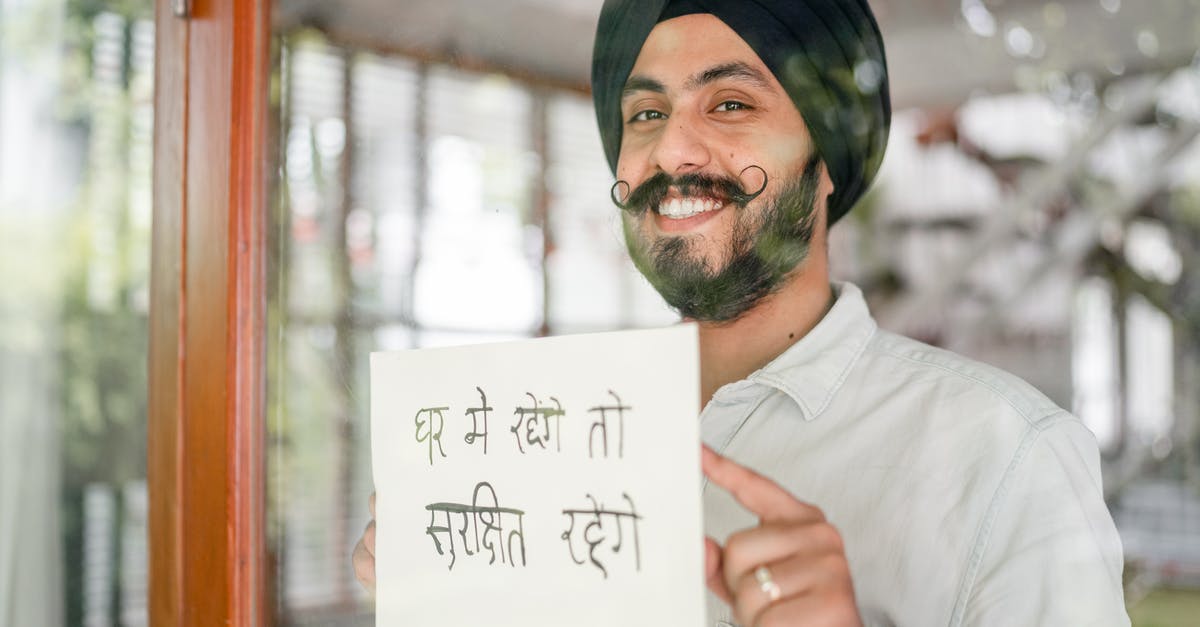 Recommend Indian cookbooks for a beginner/intermediate amateur [closed] - Positive mature modern Sikh male in turban with curly mustache leaning against glass wall with sign in indian on paper sheet and looking at camera