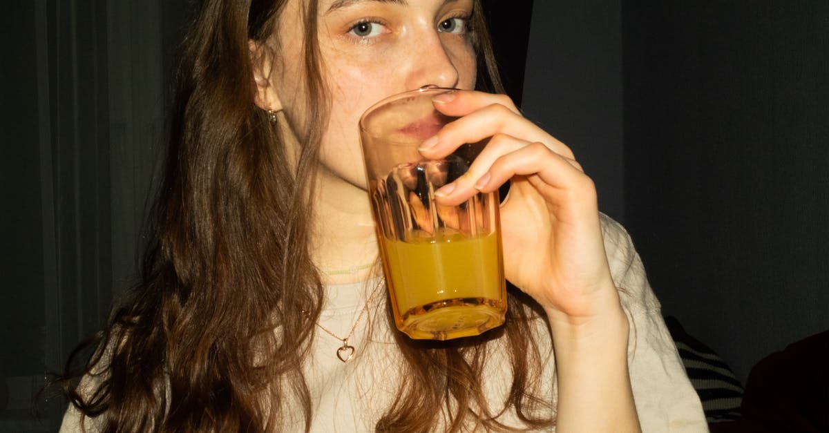 Refrigerating Clam Juice - Woman Holding Clear Drinking Glass Refrigerating Clam Juice - Woman Holding Clear Drinking Glass