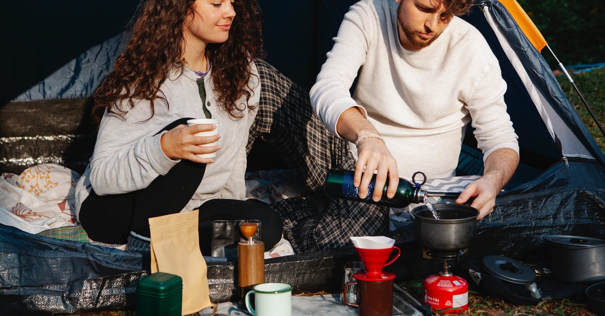 Regulating Gas Flow to a Cooktop - Crop hikers preparing hot drink in campsite Regulating Gas Flow to a Cooktop - Crop hikers preparing hot drink in campsite