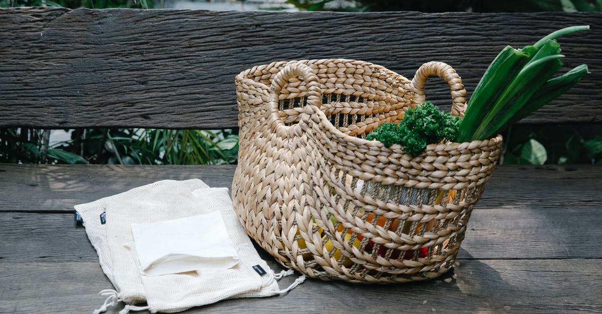 Reuse of Food Grade Tins - Wicker basket with heaped organic vegetables placed on wooden bench near reusable grocery bags in lush garden Reuse of Food Grade Tins - Wicker basket with heaped organic vegetables placed on wooden bench near reusable grocery bags in lush garden