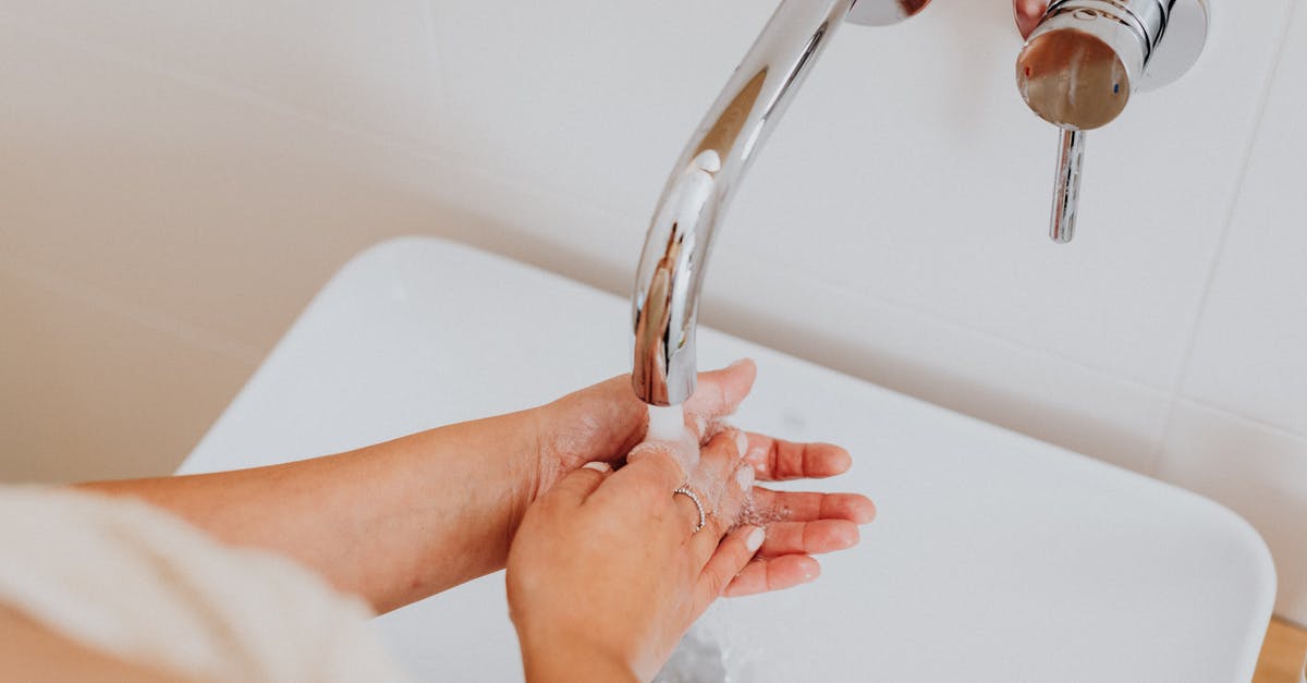 Rice: Measuring water after washing it - Person Holding Stainless Steel Faucet Rice: Measuring water after washing it - Person Holding Stainless Steel Faucet