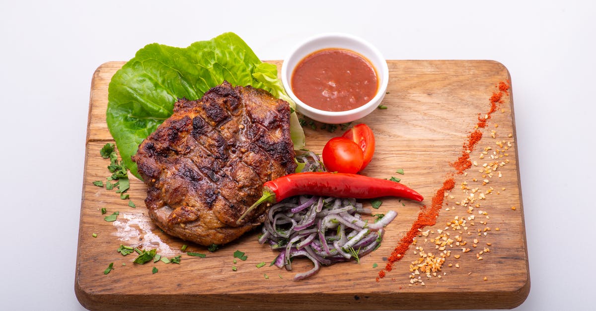 Ridding cooked food of burnt particles - A Delicious Fried Pork with Onions and Chili on a Chopping Board Ridding cooked food of burnt particles - A Delicious Fried Pork with Onions and Chili on a Chopping Board