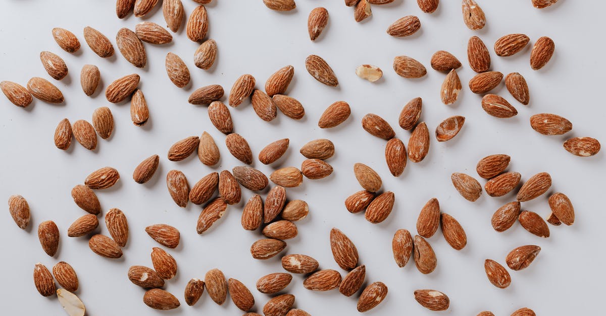 Roast almond for desserts - Top view of pile of delicious almond nuts cluttered on white table illustrating healthy food eating concept Roast almond for desserts - Top view of pile of delicious almond nuts cluttered on white table illustrating healthy food eating concept